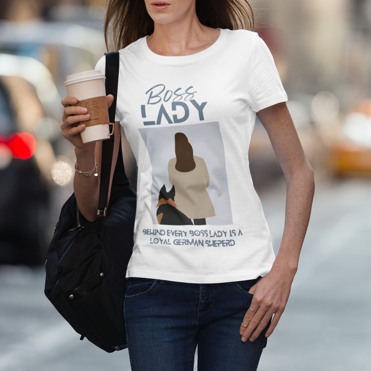 Woman wearing white Boss Lady German Shepherd t-shirt on city street with coffee and bag